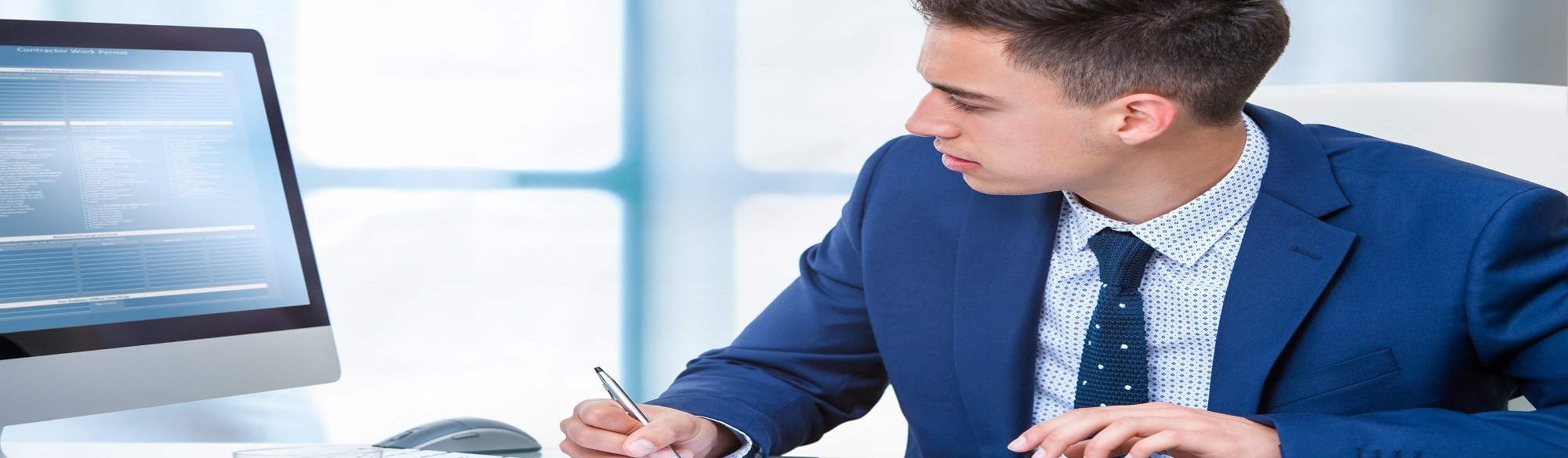 Businessman Writing and Looking at Compuiter